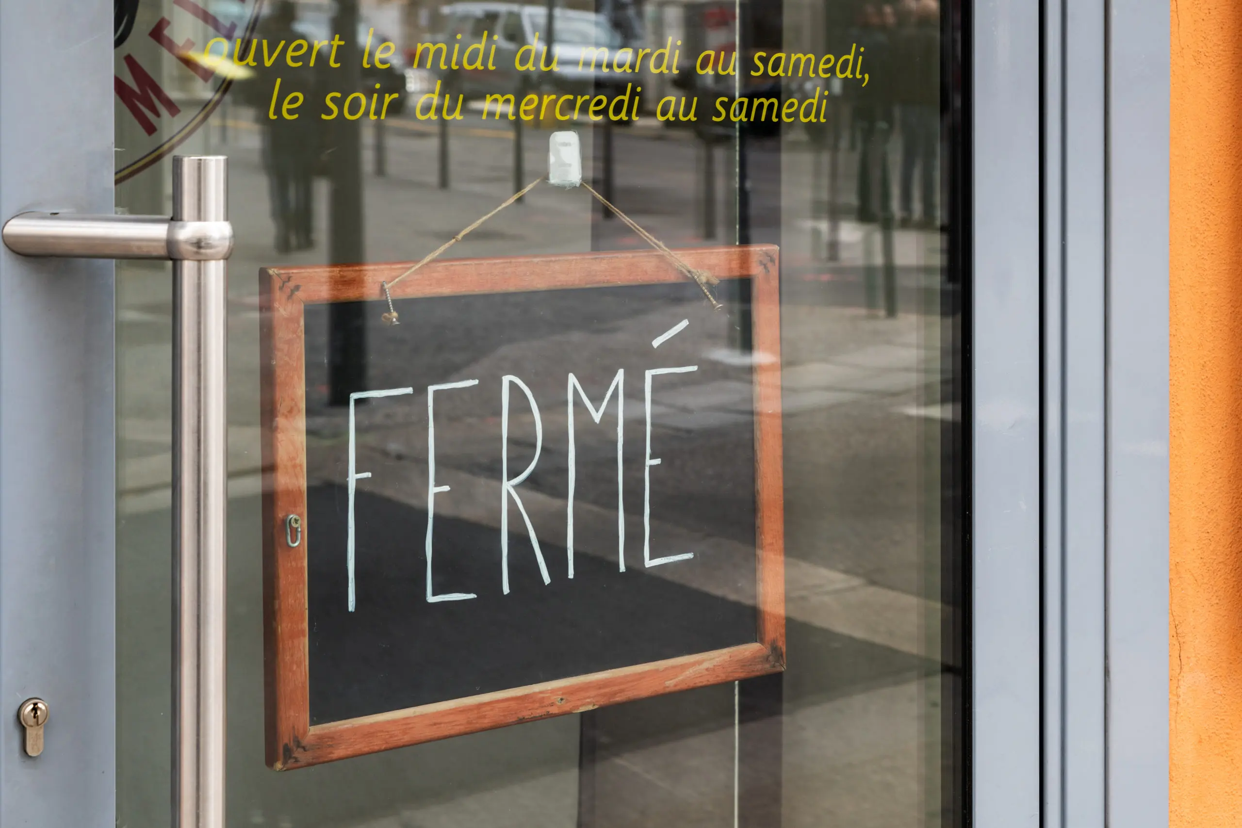 Panneau en ardoise derrière une porte vitrée indiquant : fermé